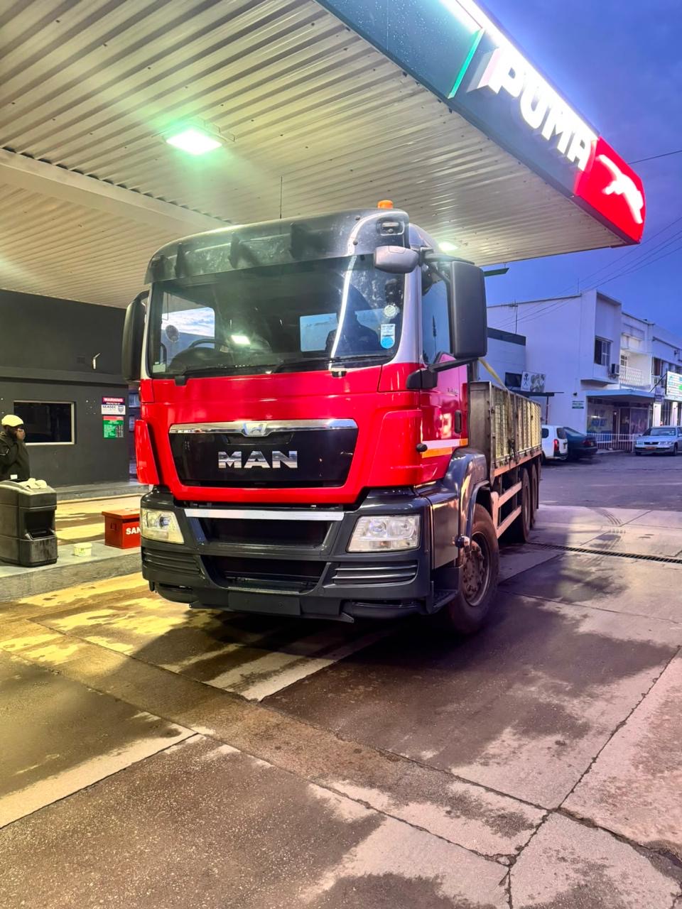 MAN grab truck at a fuel station in the evening
