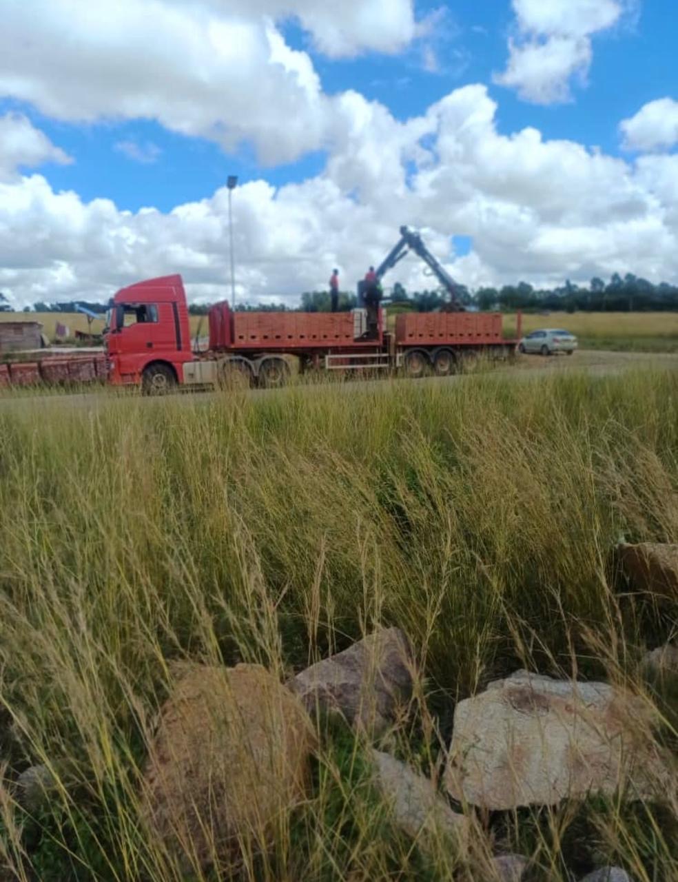 Grab truck and trailer loading bricks in an open field